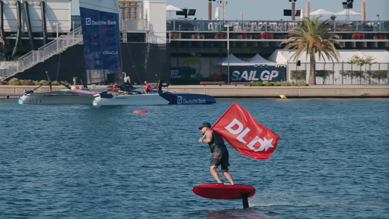 DLD Sports video preview: eFoiling racer holding a DLD flag while criss-crossing the Valencia harbor