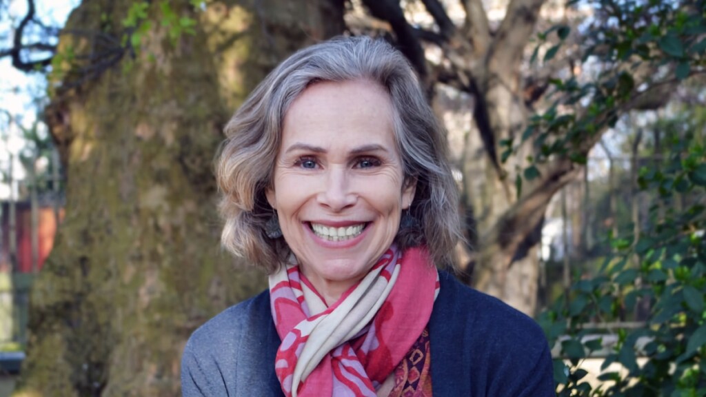 Outdoor portrait of Jane Lawton, Director of Impact at the Earth Species Project, sitting on a bench in a park.