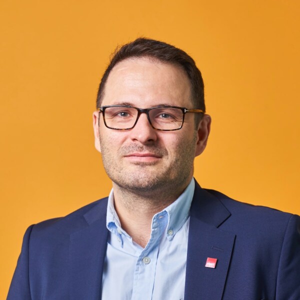 Portrait image of security researcher Dr. Florian Krampe, SPRI, in front of a yellow studio background.