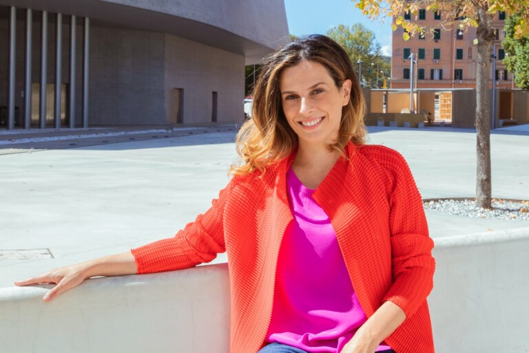 Outdoor portrait of innovation economist Francesca Bria, wearing colorful clothes, smiling at the camera.