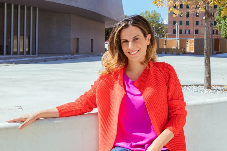 Outdoor portrait of innovation economist Francesca Bria, wearing colorful clothes, smiling at the camera.